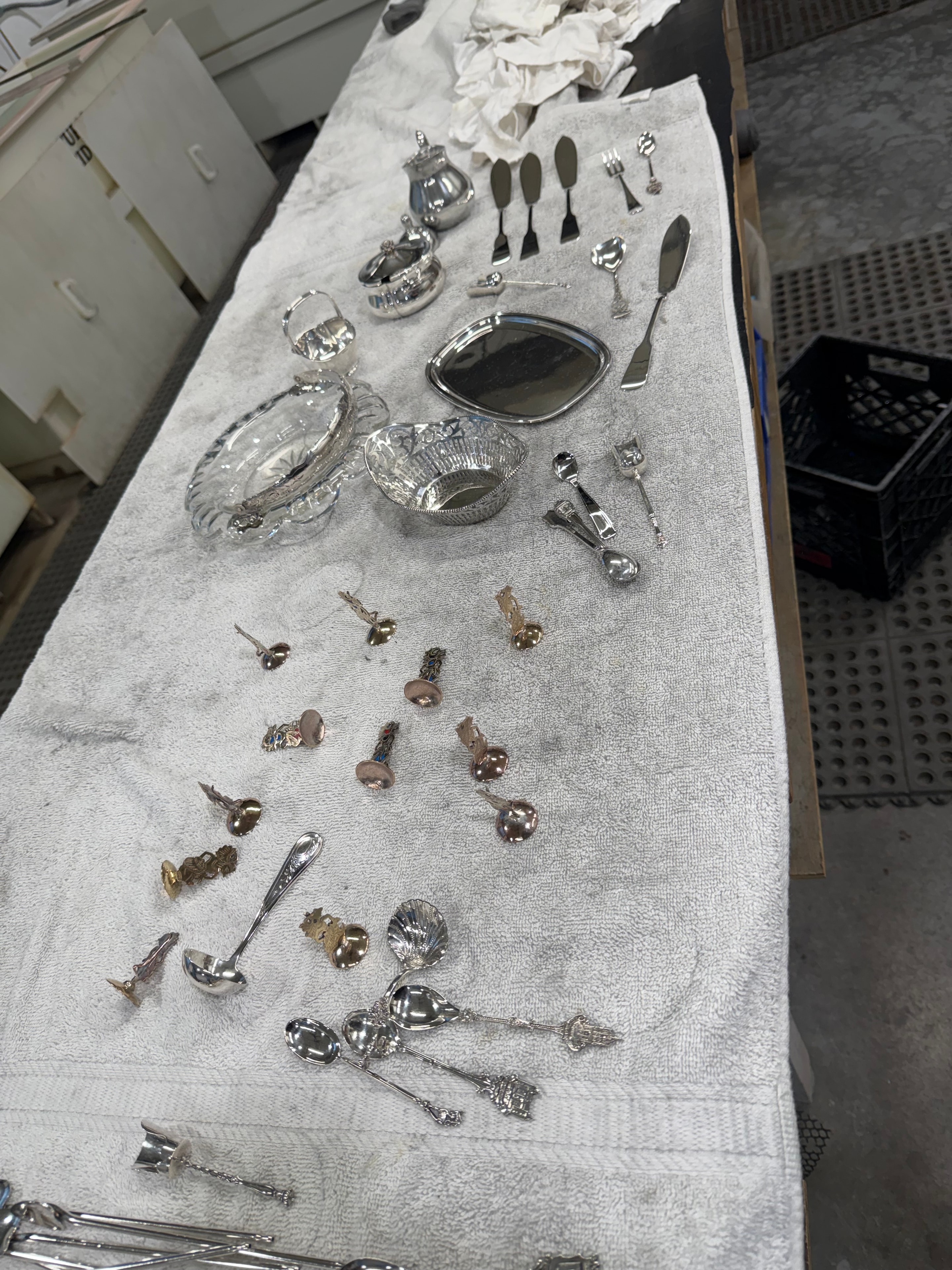 Hand-polished silverware, bowls and decorative knickknacks laid out on white cloth